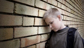 upset boy leaning against a wall